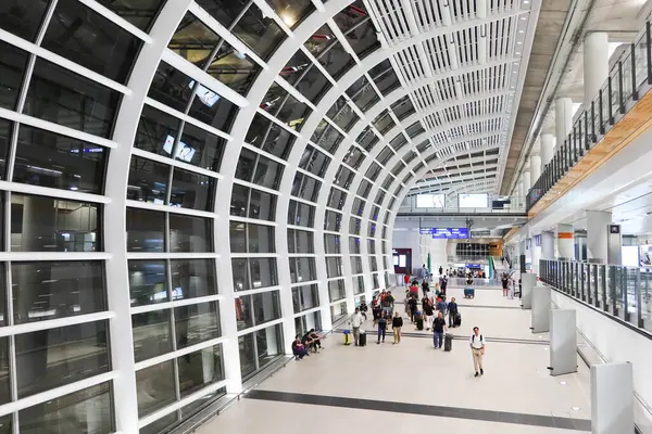 stock image Hong Kong International Airport, Hong Kong- 18 July 2024: corridor with glass canopy at night. Passengers with luggage walking on the path.