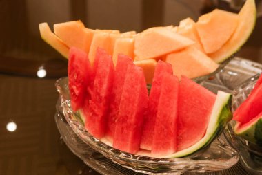 Dilimlenmiş karpuz ve kavunu cam bir tabakta deriyle kapat.