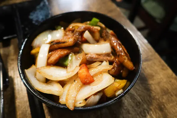 Stock image close up of Chinese style stir fried pork chop with onion, pepper in a black bowl