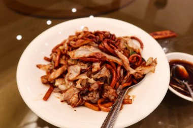 Çin usulü Şangay usulü kızarmış domuz etli erişteyi soya soslu beyaz tabakta karıştırın.