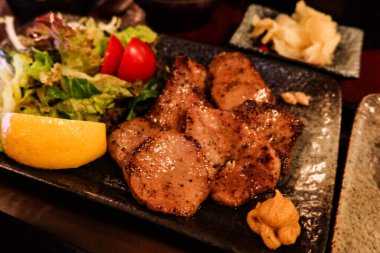 Japon sığır eti dilinin yanına siyah bir tabakta salata sebzesi koyun.