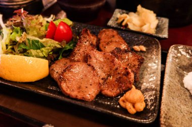 Japon sığır eti dilinin yanına siyah bir tabakta salata sebzesi koyun.