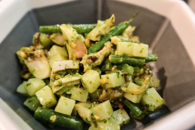 Fesleğen soslu salata ile kalamar, fasulye, sebze salatası ve altıgen şeklinde gri ve beyaz palet.