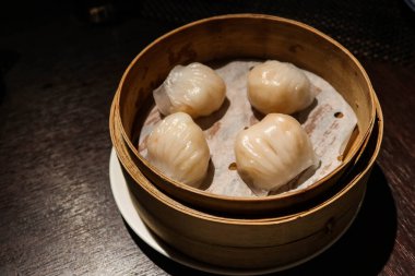 close up of steamed traditional Cantonese Hong Kong Style tea house ( yum cha) of dim sum- shrimp dumplings (har gow or ha gow or ha kao) in a bamboo steamer clipart