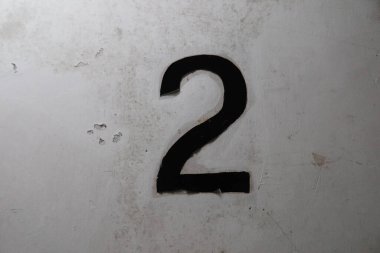 Eski ve yırtık olan beyaz duvara siyah iki numara (2 numara) yakın plan