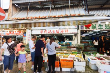 Castle Peak Bay, Tuen Mun, Hong Kong - 15 Eylül 2024: Akvaryumlarda balık ya da yengeç satın alan insanlarla birlikte deniz kenarındaki balıkçı köyündeki deniz ürünleri dükkanı