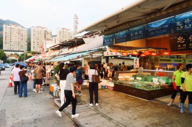 Castle Peak Bay, Tuen Mun, Hong Kong - 15 Eylül 2024: Akvaryumlarda balık ya da yengeç satın alan insanlarla birlikte deniz kenarındaki balıkçı köyündeki deniz ürünleri dükkanı