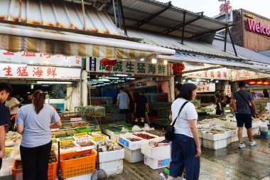 Castle Peak Bay, Tuen Mun, Hong Kong - 15 Eylül 2024: Akvaryumlarda balık ya da yengeç satın alan insanlarla birlikte deniz kenarındaki balıkçı köyündeki deniz ürünleri dükkanı