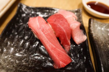 Üç parça Japon ton balıklı toro suşisini siyah bir tabakta kapatıyoruz.