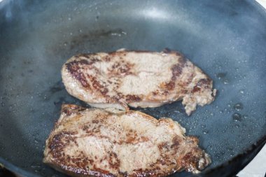 Tavada iki parça biftek pişirirken ev yapımı kızartmaya yakın çekim.