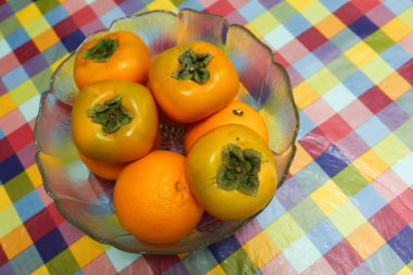 Portakalları ve hurmaları klonlanmış masa örtüsüne yerleştirilmiş cam bir kaseye koy.