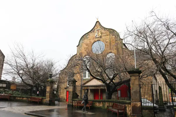 Canongate, Canongate Kirk, Old Town, Edinburgh, İskoçya - 28 Ocak 2016: Kilisenin dışındaki Edinburgh cemaat kilisesi, kışın bulutlu bir günde yaprakları dökülmeyen bir ağaçla birlikte.