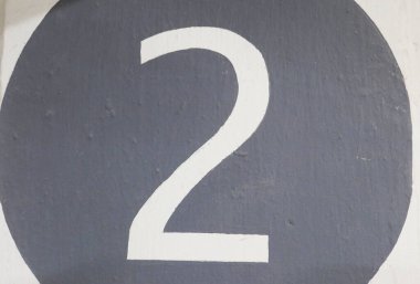 Duvarda gri yuvarlak şekilli iki numaraya yakın dur.