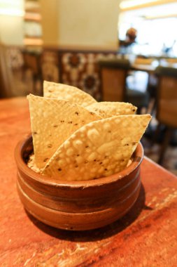 close of of Indian crispy Papadum biscuits for dipping in a brown bowl clipart