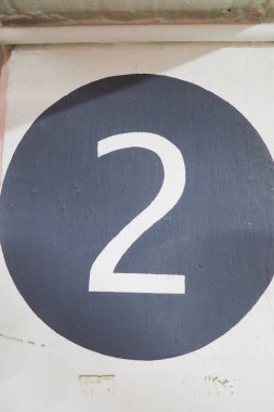 Duvarda gri yuvarlak şekilli iki numaraya yakın dur.