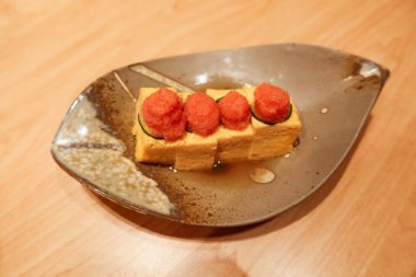 close up of Japanese Pollock roe toppings on Tamagoyaki egg on a leaf-shaped plate clipart