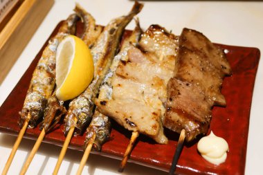 Japon kushiyaki şiş balığı, öküz dili, sığır eti, domuz eti ve Japon izakaya restoranından alınmış bir tabakta bir dilim limon..