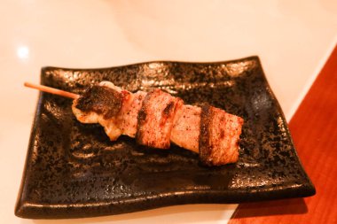 Japon deniz ürünleri yılan balığı şiş kushiyaki restoranda çekilmiş siyah bir tabakta.