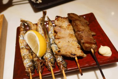 Japon kushiyaki şiş balığı, öküz dili, sığır eti, domuz eti ve Japon izakaya restoranından alınmış bir tabakta bir dilim limon..