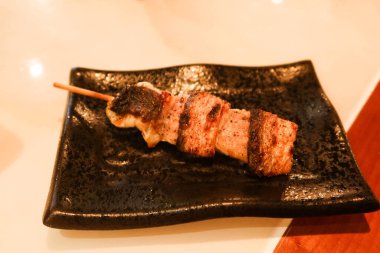 Japon deniz ürünleri yılan balığı şiş kushiyaki restoranda çekilmiş siyah bir tabakta.