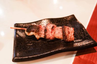 Japon deniz ürünleri yılan balığı şiş kushiyaki restoranda çekilmiş siyah bir tabakta.