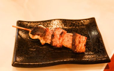 Japon deniz ürünleri yılan balığı şiş kushiyaki restoranda çekilmiş siyah bir tabakta.