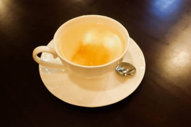 Sıcak yuzu reçelini beyaz çay fincanında limonata suyuna yakın tut.