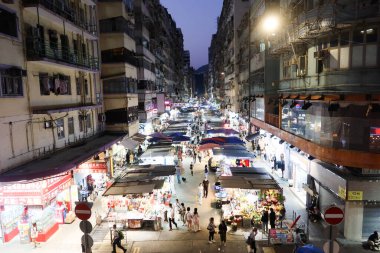 Hanımlar Pazarı, Mong Kok, Hong Kong - 12 Ekim 2024: her iki tarafında işportacı çadırı olan cadde indirimli giysi, yiyecek, bitki, meyve, gece vakti yürüyen birçok insanla birlikte hediyelik eşya satıyor.