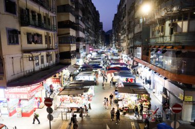 Hanımlar Pazarı, Mong Kok, Hong Kong - 12 Ekim 2024: her iki tarafında işportacı çadırı olan cadde indirimli giysi, yiyecek, bitki, meyve, gece vakti yürüyen birçok insanla birlikte hediyelik eşya satıyor.