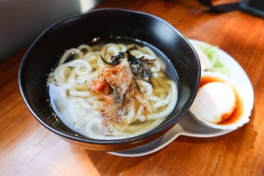 Japon çorbası udon eriştesini somon ve deniz yosunuyla kapatın. Yarım haşlanmış yumurta (onsen yumurtası) ve yanında sebze salatası.