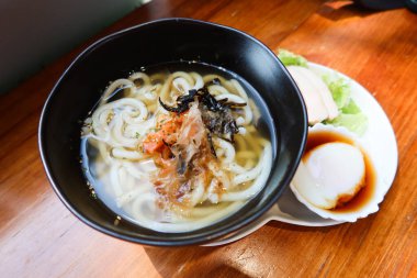Japon çorbası udon eriştesini somon ve deniz yosunuyla kapatın. Yarım haşlanmış yumurta (onsen yumurtası) ve yanında sebze salatası.