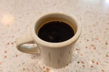 Siyah kahveyi beyaz bir fincanda beyaz mozaik desenli bir masada kapatıyoruz.