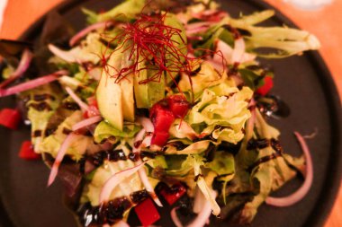 Avokado domates reçeli peyniri ve taze soğan salatasını siyah tabağa koy.