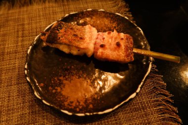 Japon şiş balığı ızgara balığını siyah tabakta yakın.