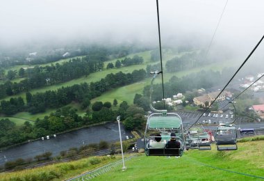 Omuro Dağı, Ito, Shizuika, Japonya - 30 Ekim 2024: açık havada sisli bir günde yeşil tepeli yolcuların bulunduğu teleferik halatı