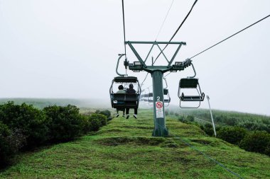 Omuro Dağı, Ito, Shizuika, Japonya - 30 Ekim 2024: açık havada sisli bir günde yeşil tepeli yolcuların bulunduğu teleferik halatı