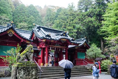 Hakone Tapınağı, Hakone, Japonya- 27 Ekim 2024: Aslan taşından heykeli olan ana binanın tapınak girişi ve tapınağın dışında insanlar ve arkada ağaçlar