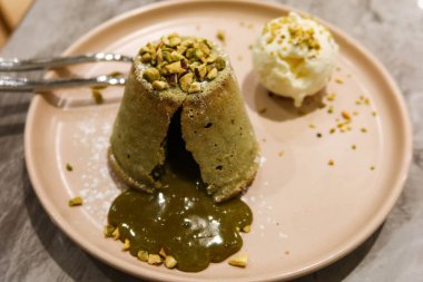 Tatlı şam fıstıklı lav keki ve yanında vanilyalı dondurma ve tabağında iki kaşık olan fındık gibi fındıklı çikolata kreması.