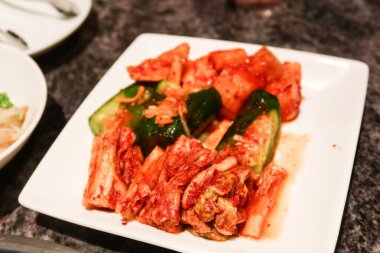 Aperatif olarak beyaz bir tabakta mayalanmış Kore kimchi, havuç ve salatalık yakın çekim 