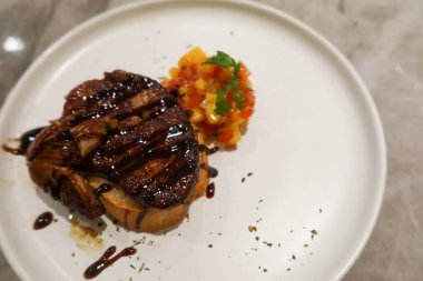Izgara Foie gras 'yı (kaz ciğeri) üzerine sos ve domates zarıyla kaplayıp beyaz bir tabakta kopyala.