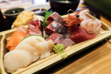 Japon saşimi çeşitlerine yakın karides, karides, balık, somon, levrek ve balık dilimlenmiş ahşap tabakta.