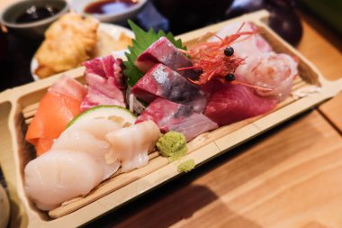 Japon saşimi çeşitlerine yakın karides, karides, balık, somon, levrek ve balık dilimlenmiş ahşap tabakta.