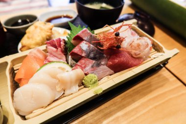 Japon saşimi çeşitlerine yakın karides, karides, balık, somon, levrek ve balık dilimlenmiş ahşap tabakta.