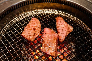 Yakiniku 'dan üç parça ızgara Japon wagyu bifteğini kömürle yakın.