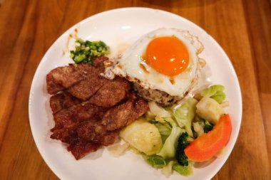 Çin usulü Hong Kong Çin usulü yağda yumurta, taze soğan yağı sosu, haşlanmış sebze (brokoli, havuç, lahana) ve kızarmış domuz pirzolası ve karışık uzun tahıllı pirinç.