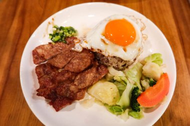 Çin usulü Hong Kong Çin usulü yağda yumurta, taze soğan yağı sosu, haşlanmış sebze (brokoli, havuç, lahana) ve kızarmış domuz pirzolası ve karışık uzun tahıllı pirinç.