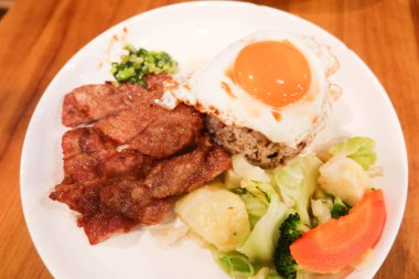 Çin usulü Hong Kong Çin usulü yağda yumurta, taze soğan yağı sosu, haşlanmış sebze (brokoli, havuç, lahana) ve kızarmış domuz pirzolası ve karışık uzun tahıllı pirinç.