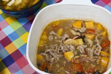 Ev yapımı Çin güvecini, tatlı patates, domates, balkabağı ve beyaz tencerede çorba ve sosla kaplayın.