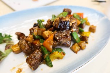 Çin usulü kızarmış wagyu bifteğini dilimlenmiş sarımsak ve karabiberle kaplayın.