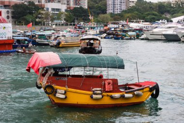 Aberdeen, Hong Kong - 16 Aralık 2024: Güneybatı Hong Kong adası kıyısı yakınında balıkçı tekneleri olan. Yüzen ünlü köyün sahil şeridi boyunca inşa edilen yüksek konut kuleleri